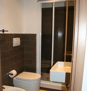 A bathroom with a toilet, a sink, and a shower area. - Inncentral Rome (Rome)