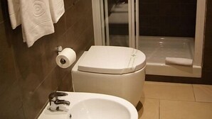 A bathroom with a toilet, bidet, and a glass-enclosed shower.