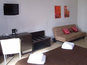 A hotel room with a bed, a sofa, a TV, a coffee maker, and artwork on the wall. - Inncentral Rome (Rome)