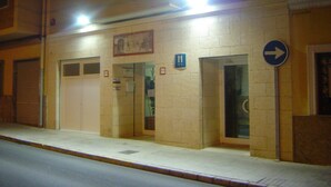 Un edificio con un cartel que indica un hospital. Se observan puertas y ventanas, y una señal de dirección en la acera.