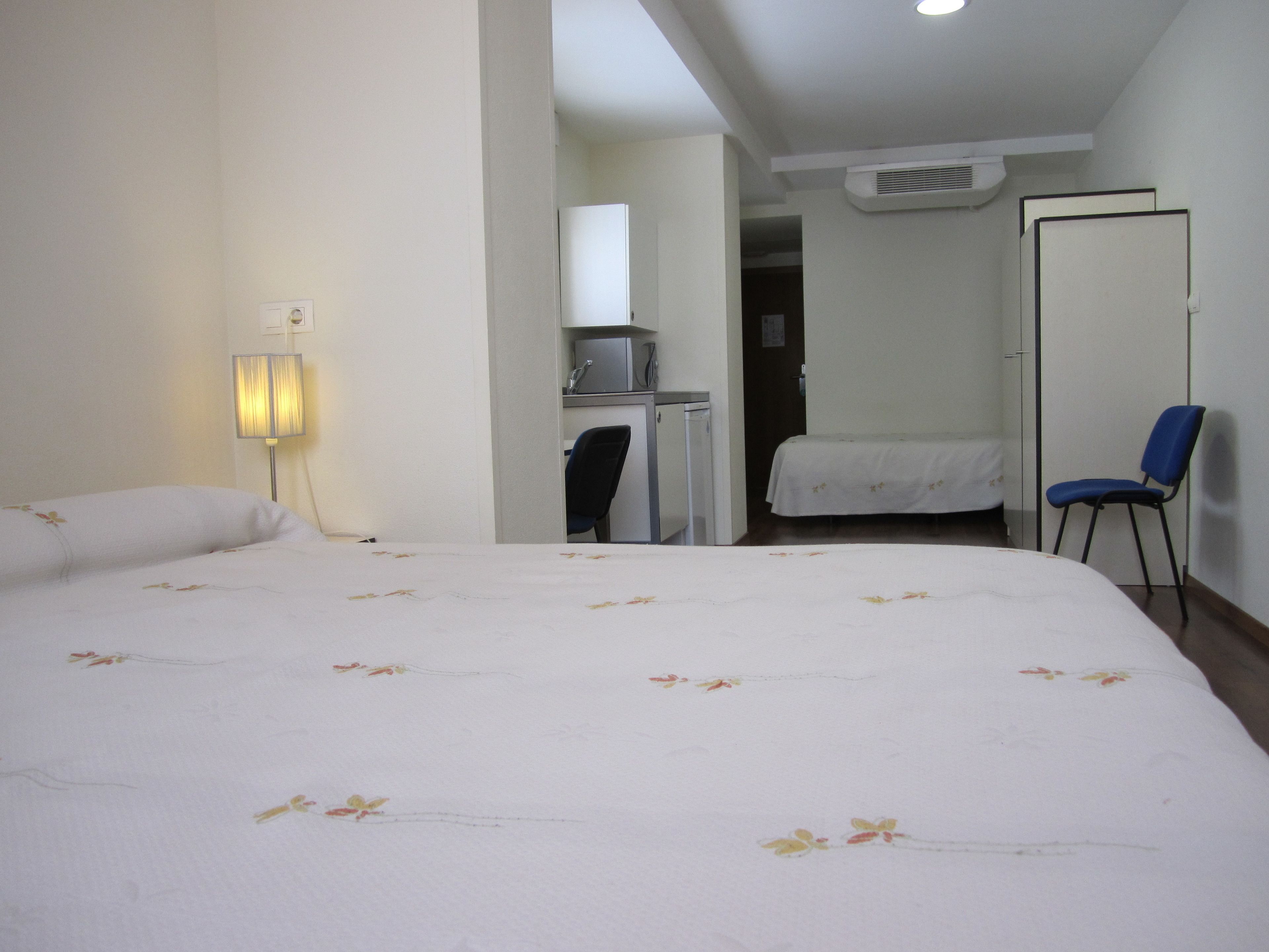 Una habitación de hotel con una cama grande, un escritorio, una silla y un armario.