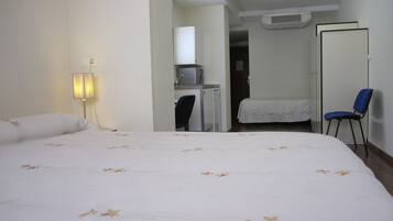 Una habitación de hotel con una cama grande, un escritorio, una silla y un armario.