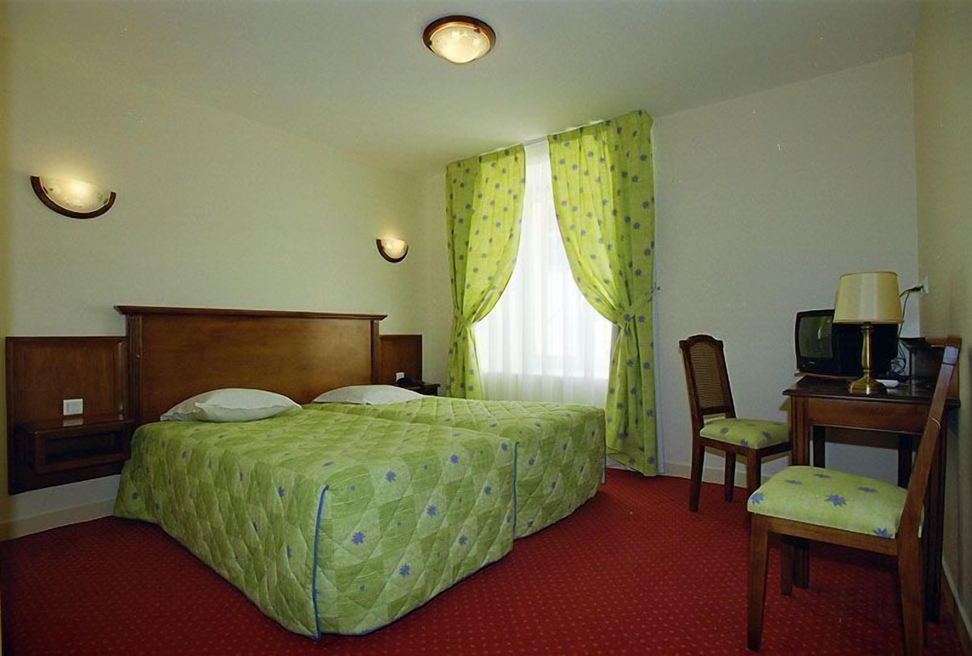 Ett hotellrum med två sängar, en tv, ett skrivbord och en stol.