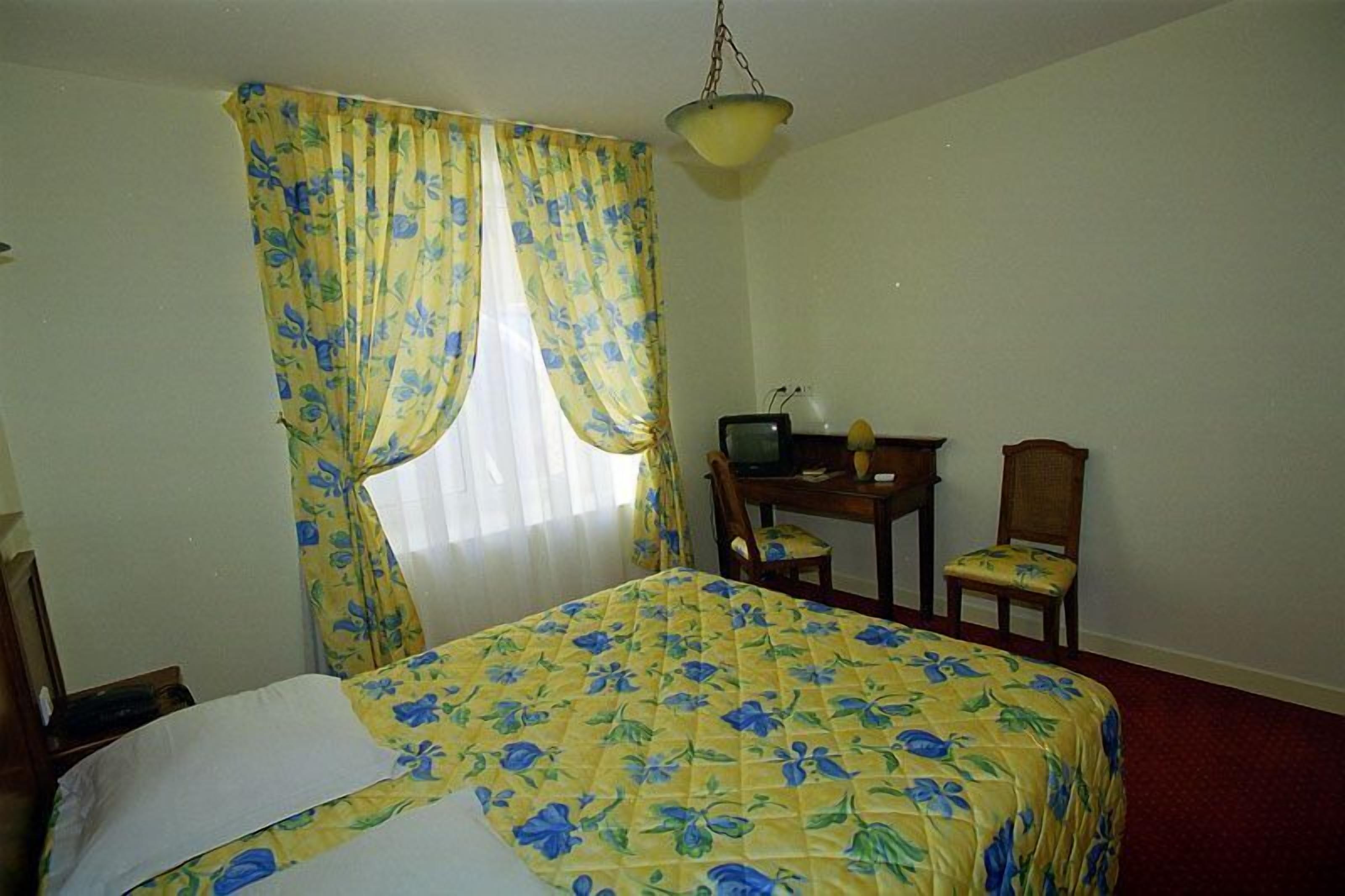 Una habitación de hotel con una cama, un escritorio y una silla.