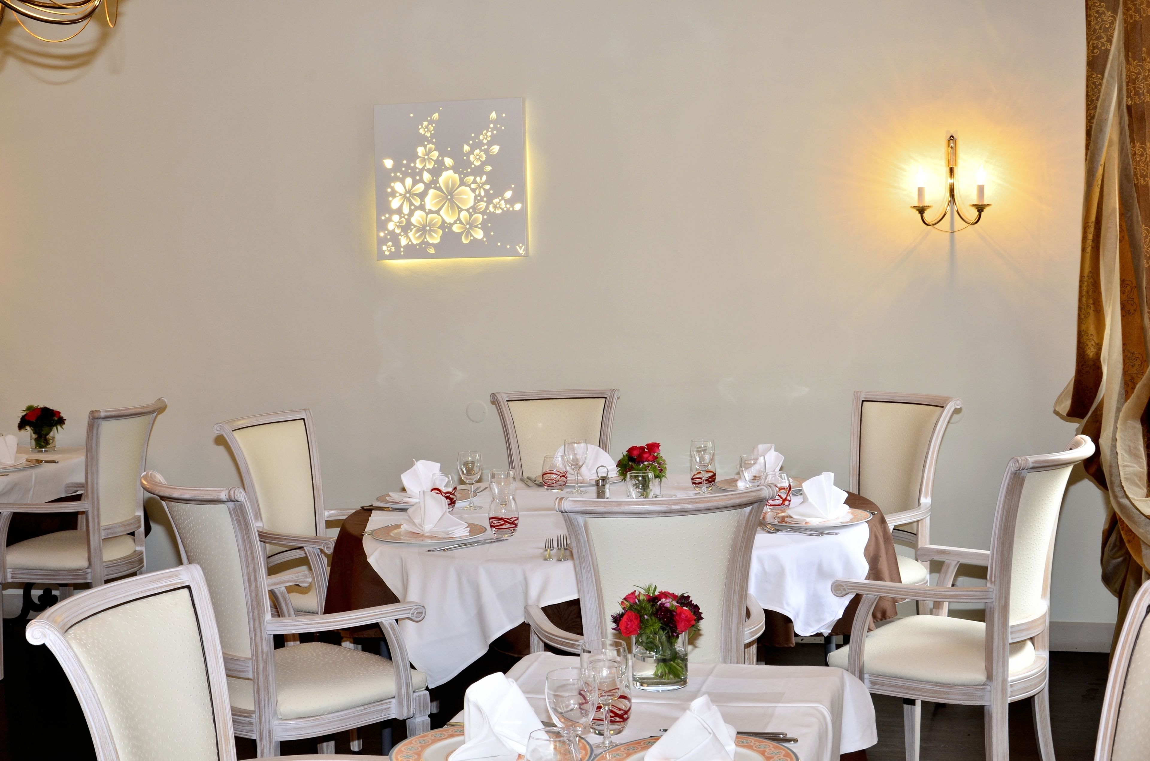 A dining area with round tables, white tablecloths, and chairs.