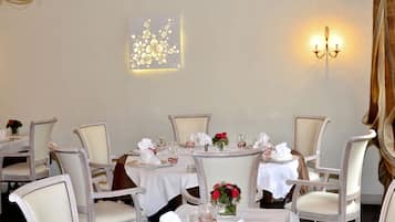 A dining area with round tables, white tablecloths, and chairs.