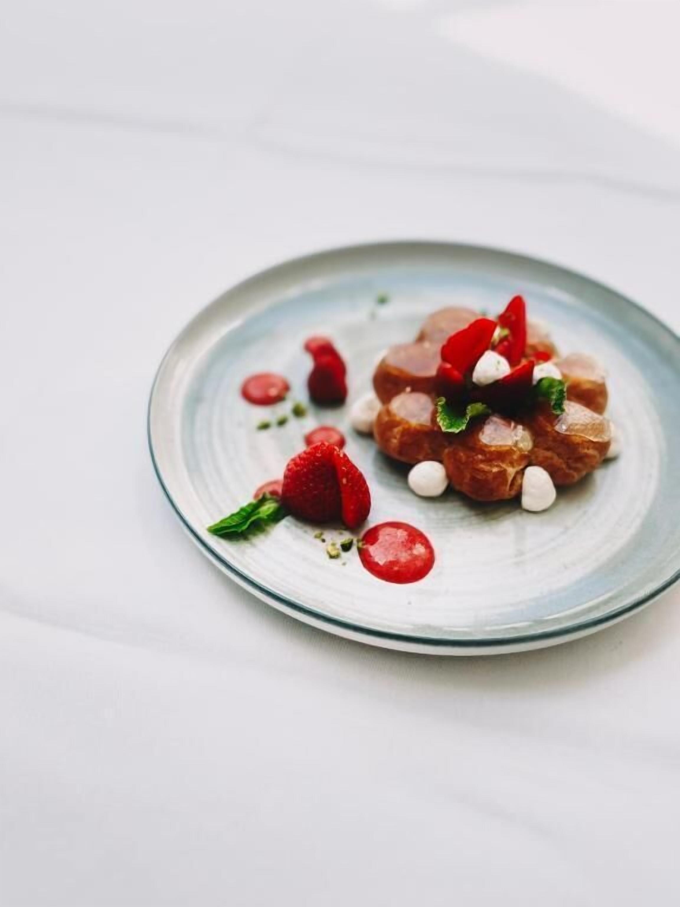 Un dessert présenté dans une assiette, composé de fraises et de petites boules blanches.