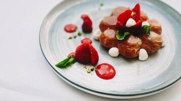Un dessert présenté dans une assiette, composé de fraises et de petites boules blanches.