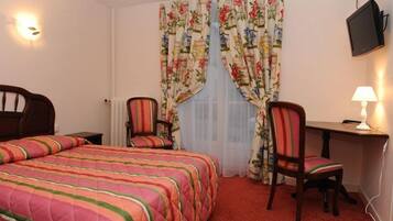 A hotel room with a bed, a desk, a chair, a TV, and curtains.