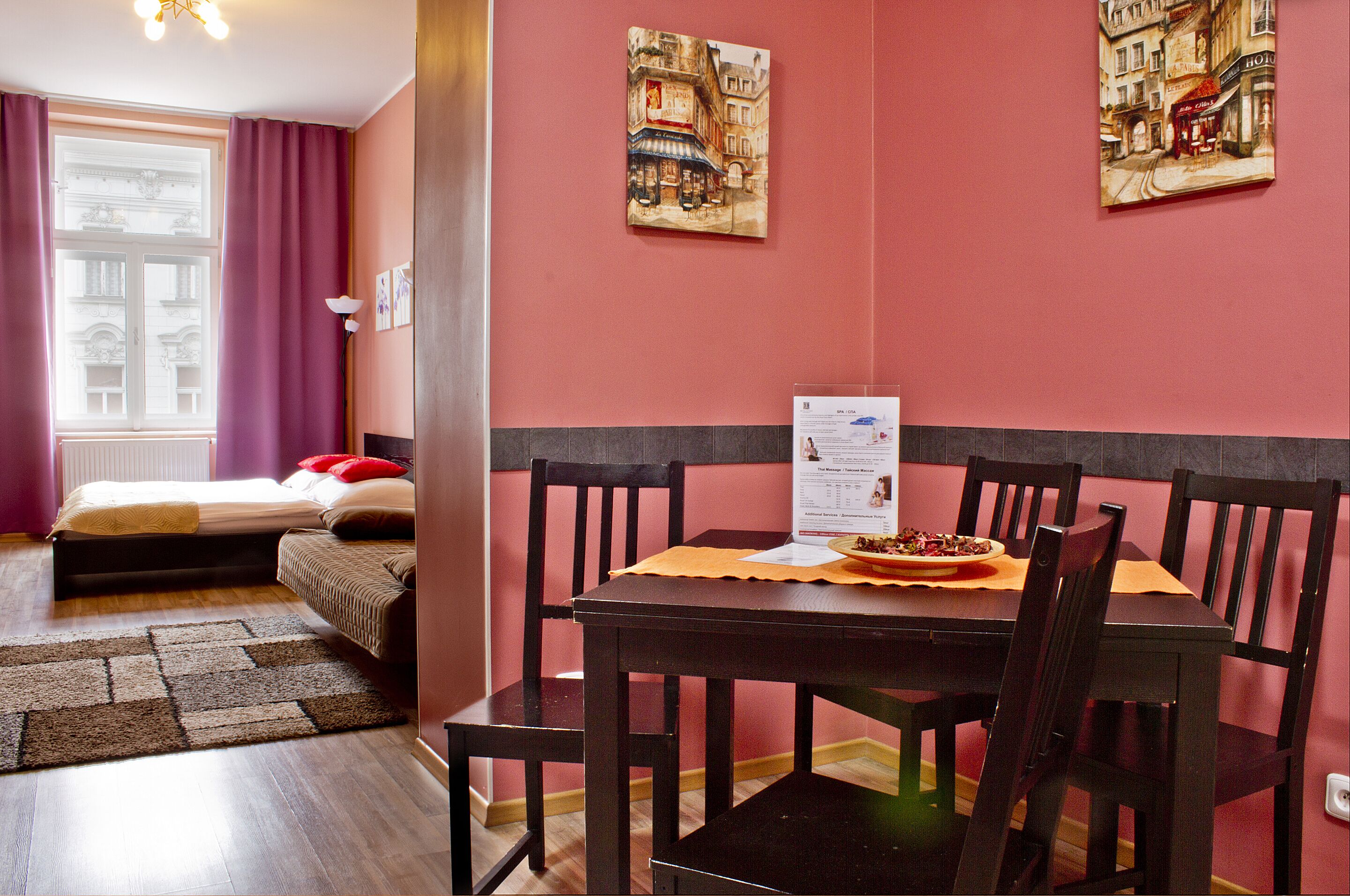 Ein Zimmer mit einem Bett, einem Esstisch mit Stühlen und zwei Bildern an der Wand.