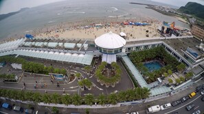 Un gran hotel con una estructura cúpula central, piscina y zona de playa con sombrillas.