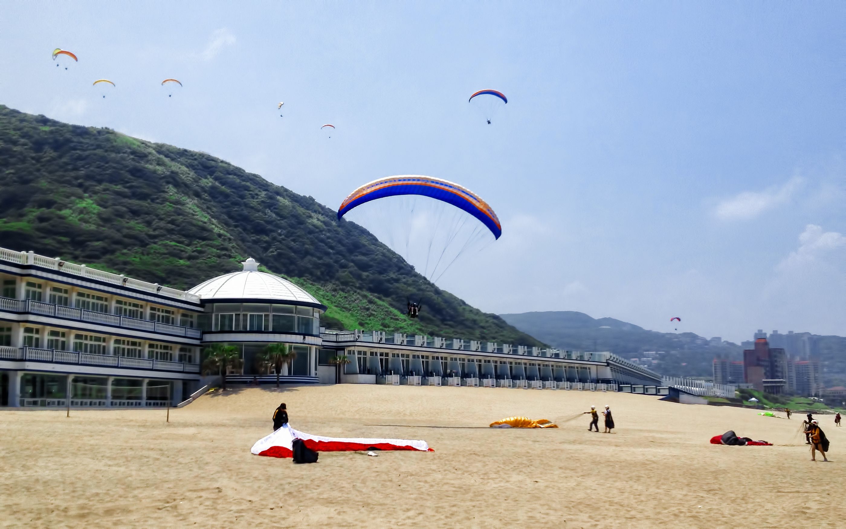 A beach with a building featuring a large dome and multiple balconies.