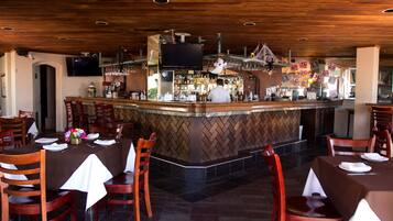 A restaurant with a bar area, wooden ceiling, and tiled floor.