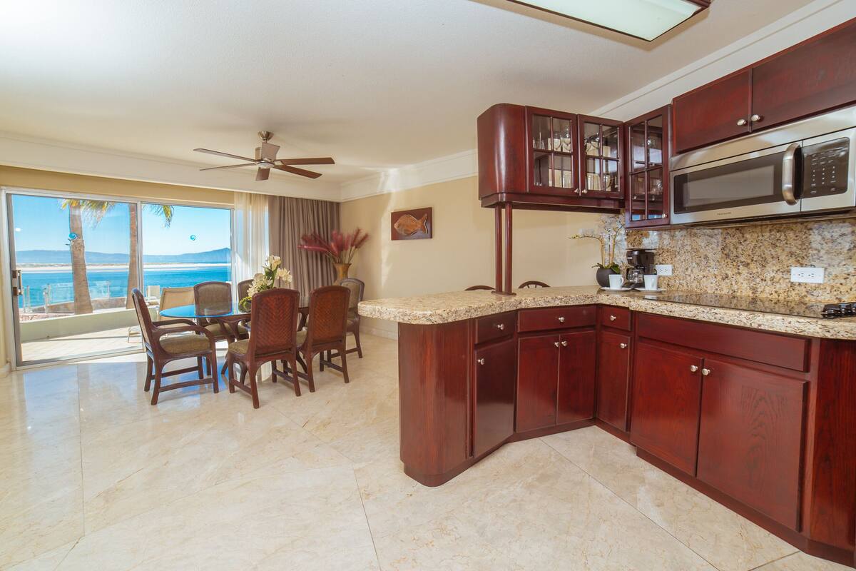 A kitchen with granite countertops, wooden cabinets, and a built-in microwave.