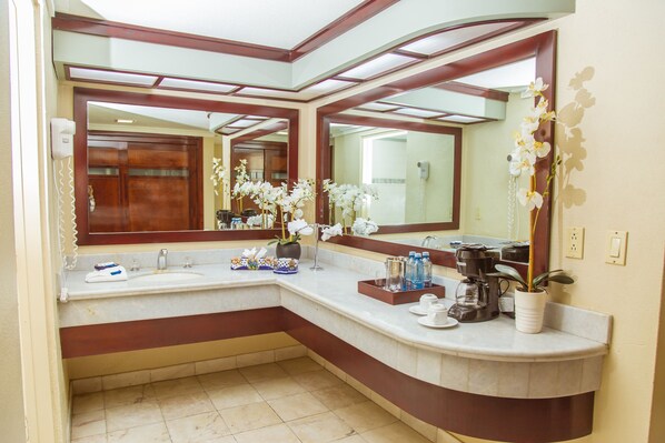 Un baño moderno con un espejo grande, un lavamanos y una cafetera.