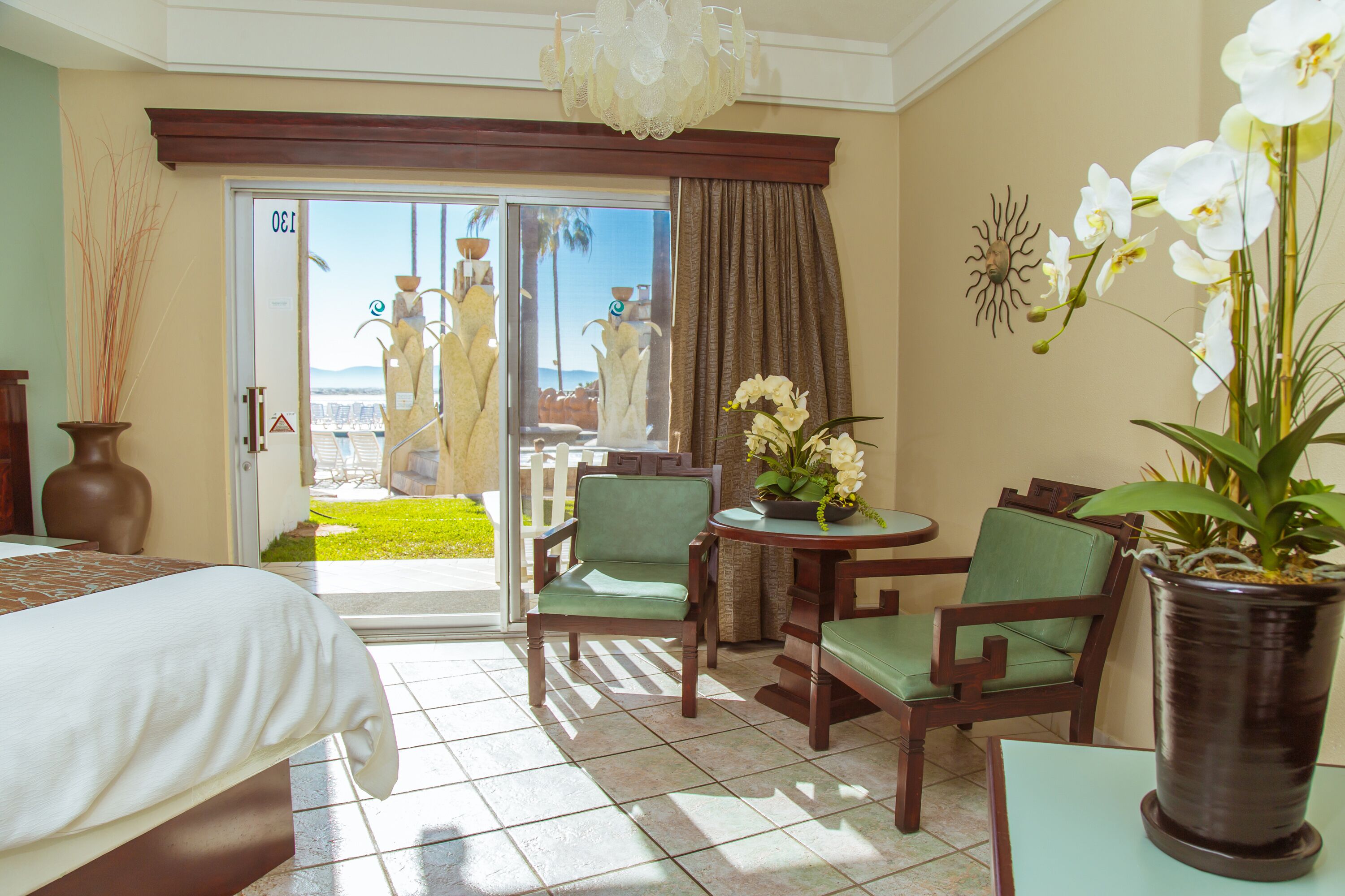 Hotelkamer met een bed, twee stoelen, een tafel, een bloempot en uitzicht op de omgeving.
