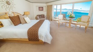 A hotel room with a large bed, a sofa, a dining table, and a view of the sea. - Estero Beach Hotel & Resort (Ensenada)