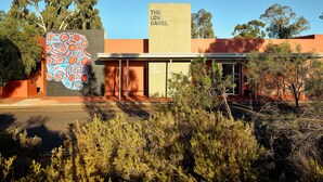 A building with a sign reading "The Lost Camel" and a colorful abstract mural on the left. - The Lost Camel (Yulara)