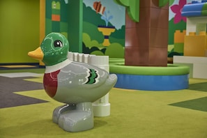 A toy duck on a green carpet with a tree and colorful background. - Legoland Windsor Resort Hotel (Windsor)
