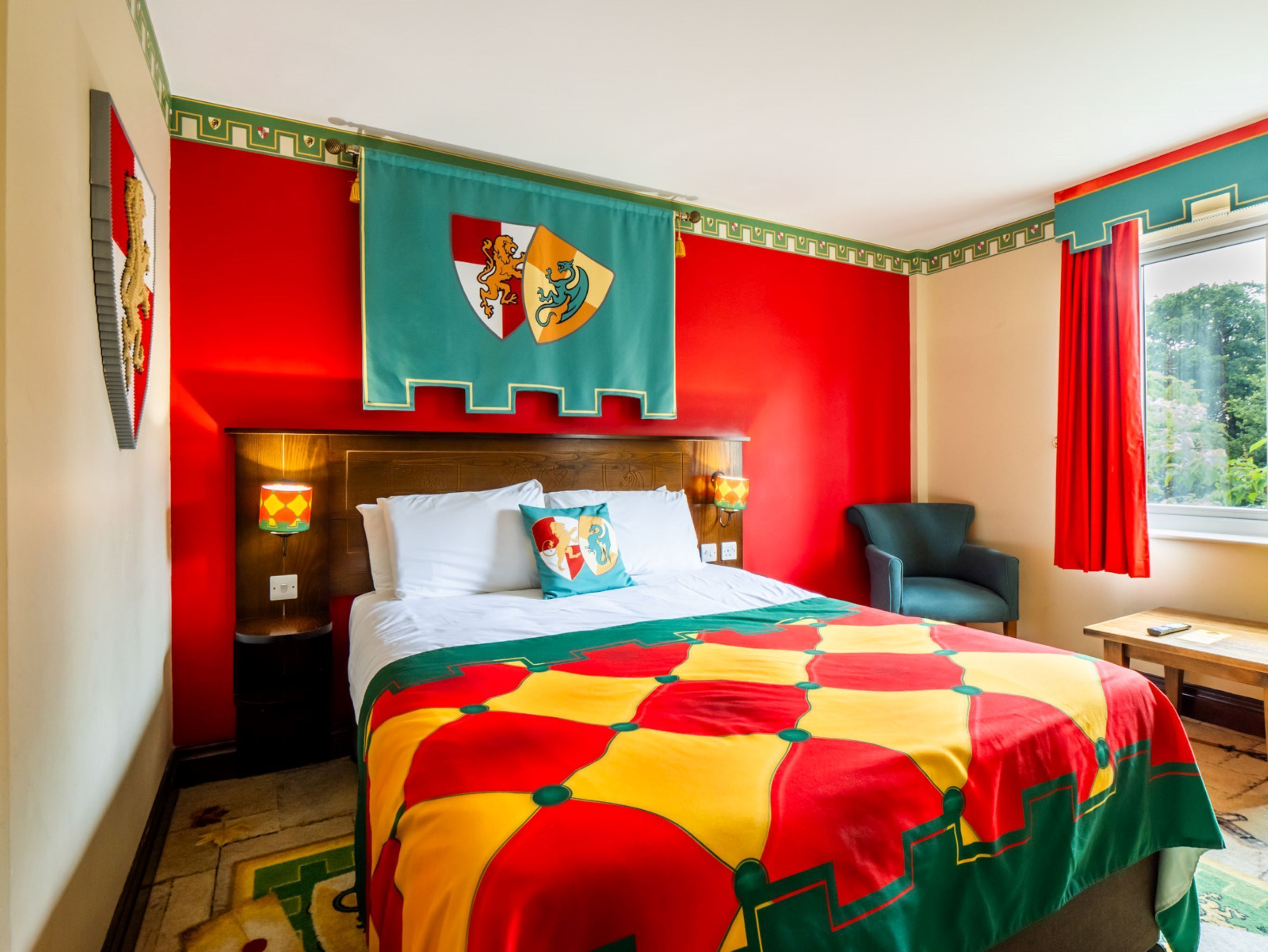 A hotel room with a bed, a chair, a nightstand, and a window with curtains.