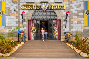 The entrance to the LEGO Castle Hotel with a stone facade, red curtains, and LEGO statues. - Legoland Windsor Resort Hotel (Windsor)