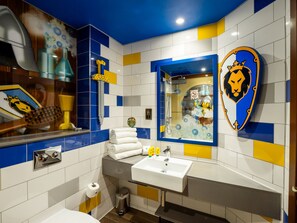 A bathroom with a sink, mirror, and a decorative wall with a lion emblem. - Legoland Windsor Resort Hotel (Windsor)