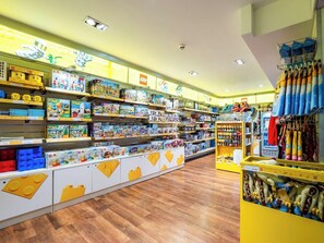 A brightly lit toy store with shelves stocked with various toys and games, a section with plush toys, and a display of LEGO sets. - Legoland Windsor Resort Hotel (Windsor)