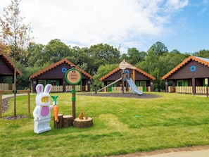 A children's play area with wooden playhouses, a slide, and a large bunny statue. - Legoland Windsor Resort Hotel (Windsor)