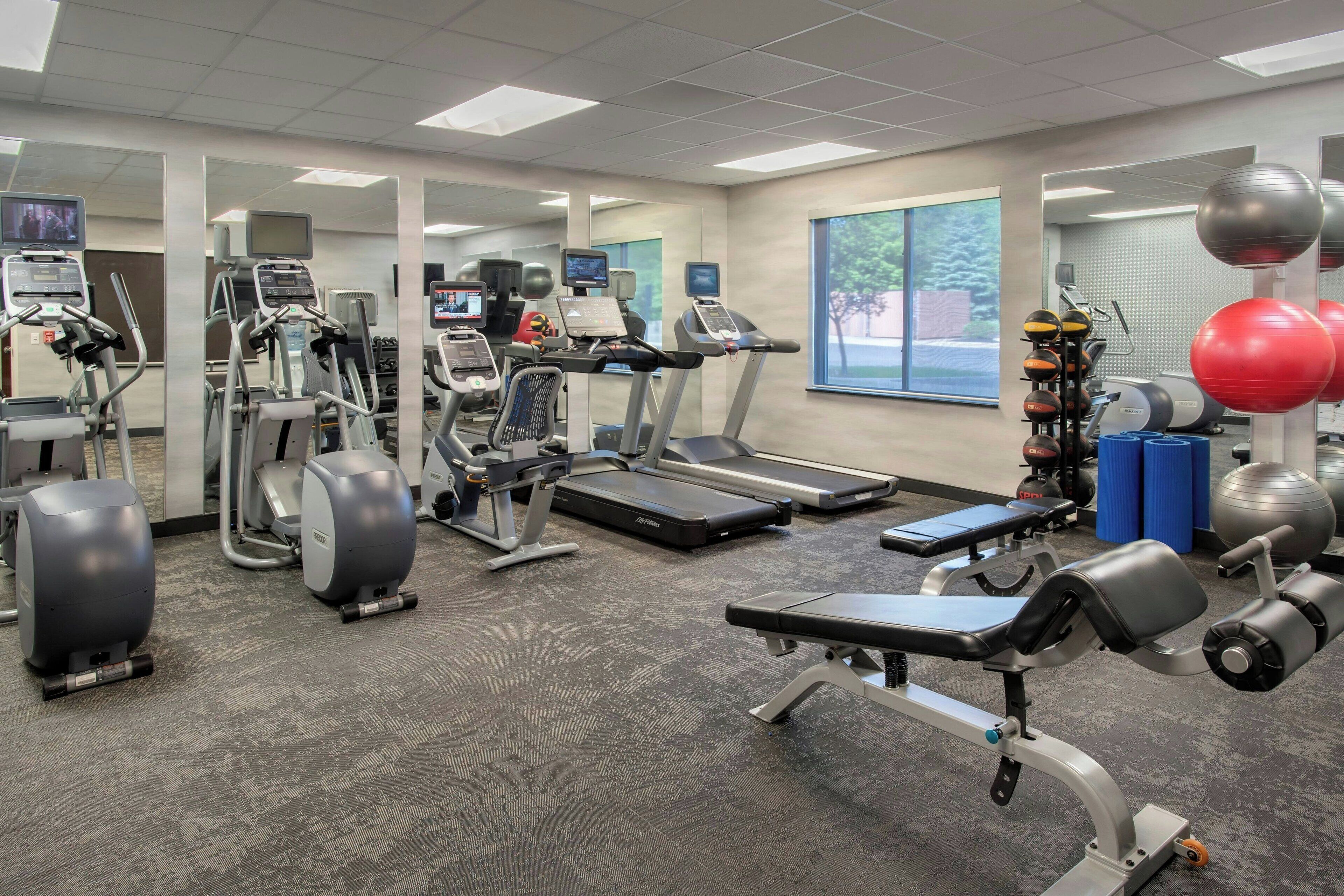 A gym with cardio machines, weightlifting equipment, and exercise balls.