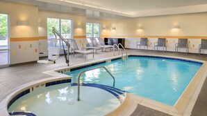 Une piscine équipée d’un espace vestiaire, de chaises longues et d’un coin avec un jacuzzi.