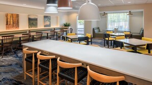 Un espace de restauration moderne, doté de plusieurs tables et chaises, d’un éclairage suspendu et d’œuvres d’art accrochées aux murs.