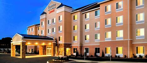 Ein mehrstöckiges Hotel mit markantem Eingang, überdachter Lobby und gut beleuchteter Fassade.