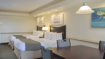A hotel room with two beds, a dining table, and a painting of a sea turtle on the wall.