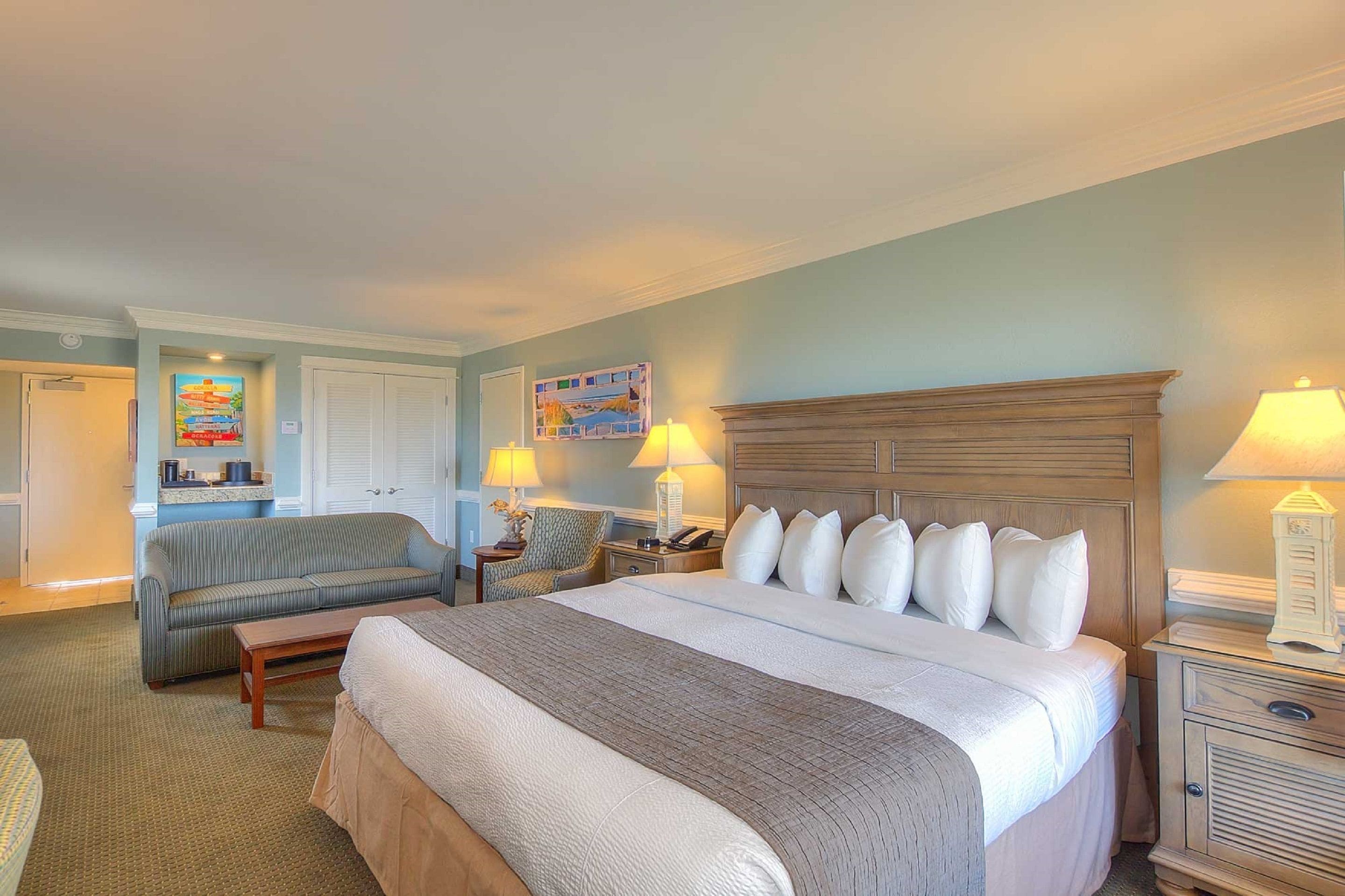 Habitación de hotel con una cama grande, un sofá, un escritorio y una lámpara.