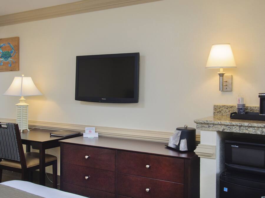Hotelkamer met flatscreen televisie, bureau met lamp, stoel, dressoir, magnetron en koffiezetapparaat.