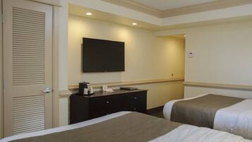 A hotel room with two beds, a flat-screen TV mounted on the wall, a dresser, and a door with a louvered design.