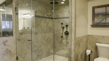 A modern bathroom with a glass-enclosed shower, a toilet, and a tiled floor.