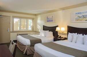 Quarto de hotel com duas camas, uma mesa e uma janela com persianas.