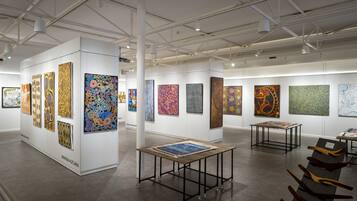 An art gallery with various paintings displayed on walls and tables.