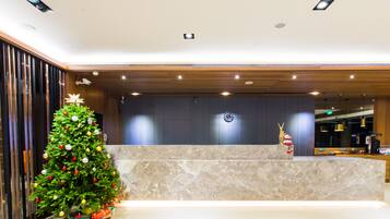 Un área de recepción con un árbol de Navidad, mostrador de mármol y un reloj en la pared.