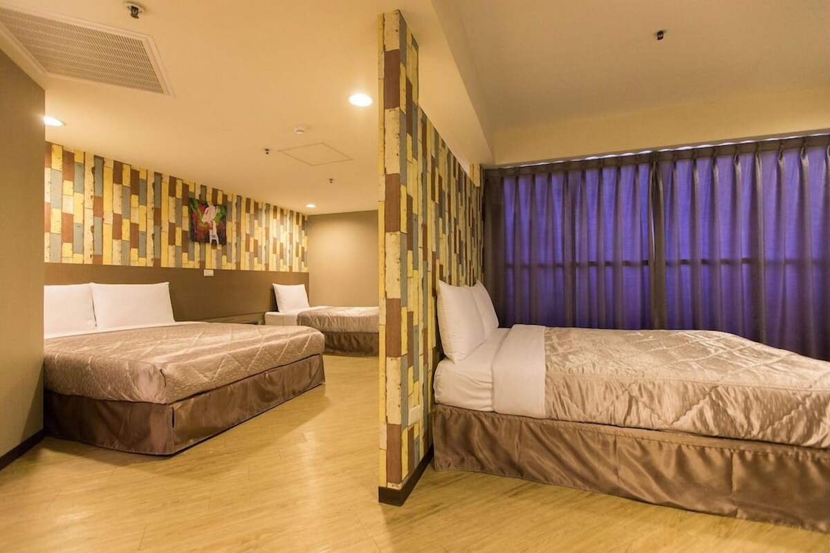 A hotel room with two beds, a small table, and a decorative wall.