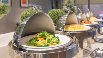 Servicio de comidas tipo buffet con recipientes cubiertos, incluyendo un plato de brócoli, en un entorno moderno con una paleta de colores neutros.