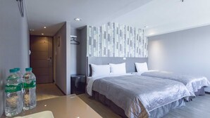 A hotel room with two beds, a bedside table with a cup and water bottles, a wall-mounted light fixture, and a door leading to another room. - Palmer Hotel (Taichung)