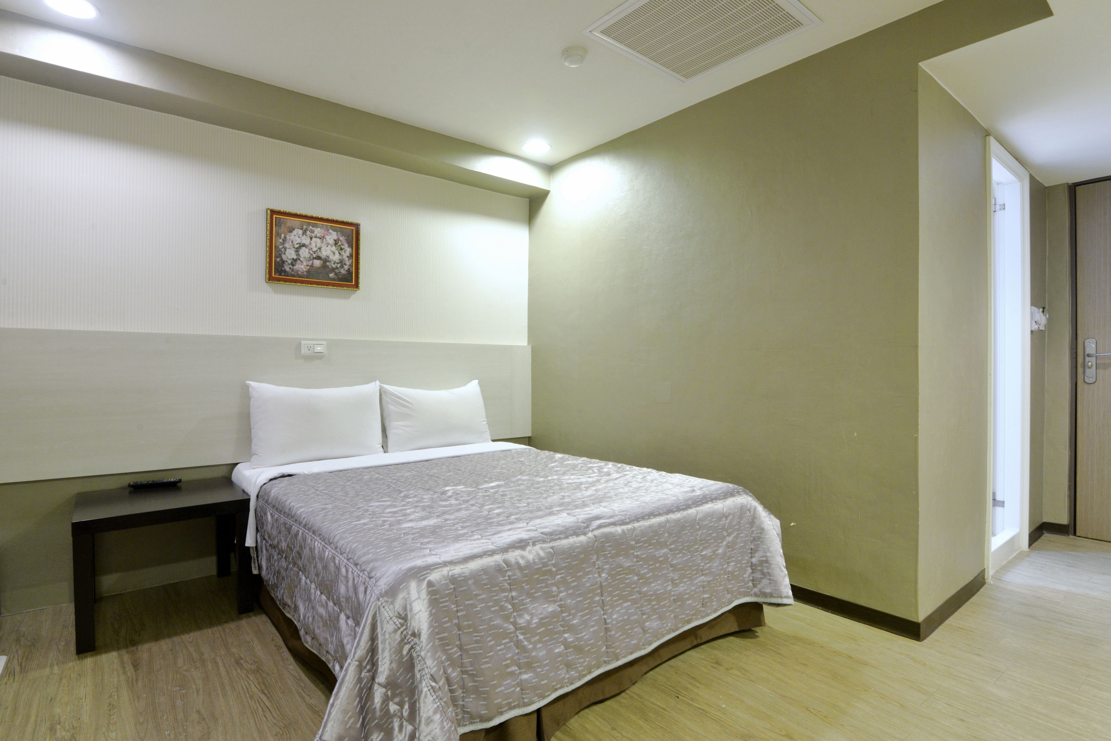 Habitació d'hotel amb un llit, una taula de nit i un quadre al mur.