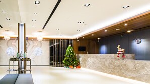 A modern lobby with a reception desk, a Christmas tree, and a large chandelier. - Palmer Hotel (Taichung)
