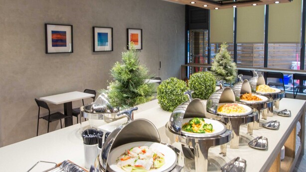 A buffet setup with multiple food stations, a small Christmas tree, and a seating area with tables and chairs. - Palmer Hotel (Taichung)