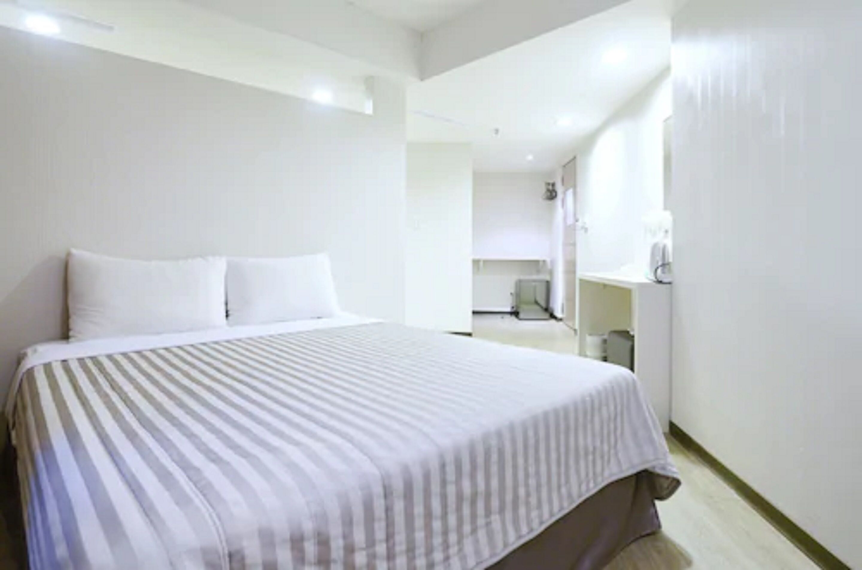 Une chambre d’hôtel avec un grand lit, un petit bureau et une fenêtre.