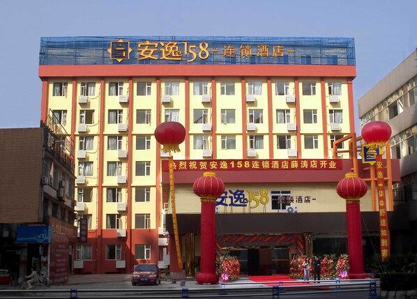 A hotel with a prominent sign reading "安逸158连锁酒店".