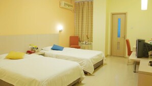A hotel room with two beds, a desk, a chair, a TV, and a window with curtains.