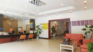A hotel reception area with a reception desk, seating area, and informational posters on the walls.